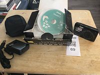 Photo of Nikon CoolPix 4400 box, camera, charger, USB cable, soft carrying case, and software CD on table.