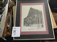Full view of framed print showing the Denny Auditorium building in black and white with pink and black matting around the print.