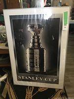 Front view of the framed Stanley Cup poster showing the trophy in black and silver tones with white mat and metal frame.