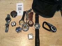 All watches and carabiner style watch laid out on table with black pouch in the background.