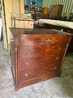 Front and side view of wooden dresser showing carved accents and brass hardware on four drawers.