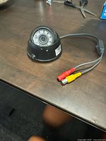 Single Bolide BC1709 dome security camera on a dark surface showing IR LEDs and attached cables with red and yellow connectors.