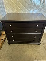 Front view of the 3-drawer wooden dresser showing dark brown finish and square silver handles on drawers.