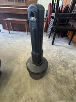 Full view of tall black cigarette disposal bin with textured surface and round base