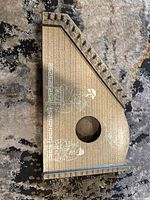 Top view of the zither showing full body, 10 strings, and decorative painted musicians and lyre motifs.