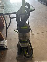 Front view of upright Hoover Powermax Pet carpet cleaner showing attached hose coiled around handle and bottom cleaning head.