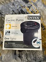 Front view of the Intex Quick-Fill Electric Pump packaging showing the product name, brand, 12V DC power source, and warnings.