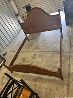 Full bed frame showing medium brown wood and curved cane inset headboard and matching footboard with carved posts.