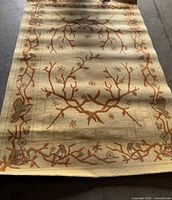 Photo showing the almond white area rug with botanical branch, bird, and abstract pattern along border.