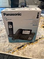 Front of product box showing Panasonic KX-TGF382 phone system with image of base station and cordless handset, highlighting Link2Cell, call block, long range, and Bluetooth features.