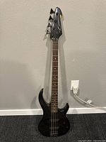 Full front view of the black electric bass guitar showing body, neck, strings, and headstock.