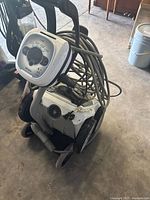 Polaris robotic pool cleaner with attached AquaLink control and bundled cables, showing the full device with wheels and control panel visible.