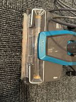 Close-up of vacuum's DuoClean head showing transparent roller brush and body in blue and grey.