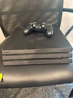 Front angled view of Sony PlayStation 4 Pro console with the DualShock 4 controller resting on top.