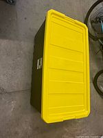 Storage tote closed, showing yellow lid and black base.