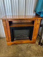 Front view of the complete electric fireplace unit with wooden mantel, showing carved details and fluted columns.