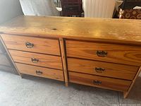 Top front view of wooden dresser showing six drawers with metal handles and natural wood texture.