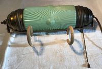 Front view showing green ribbed glass cylinder, metal end caps, wooden hooks, pull chain