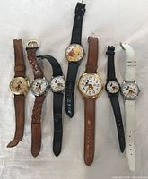 Seven Mickey Mouse wristwatches laid out