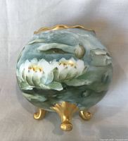 Front view of spherical porcelain vase with water lily design and gilt feet