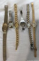 All six watches laid out side by side on white cloth