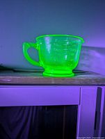 Cup glowing bright green under UV light showing fluorescence