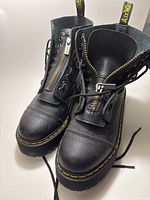 Full view of both boots showing zipper, laces, leather texture, yellow stitching