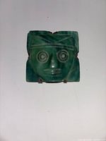 Front view showing carved green stone mask in silver setting