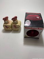 Front view of Shawnee salt & pepper shakers beside boxed KitchenAid baking cups