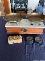 Full view of balance scale with brass pans, brass weight set, and two cast-iron weights