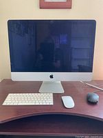 Front view of Apple iMac with keyboard and two mice on desk