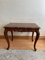 Front view of carved wood side table showing top, apron, cabriole legs