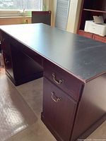 Full view of desk showing black top and wood finish