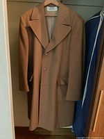 Front view of tan cashmere coat showing lapels, buttons and flap pockets