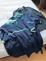 Three shirts on hangers displayed on bed