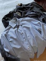 Overview of three shirts laid out: pinstripe, dark grey, charcoal.