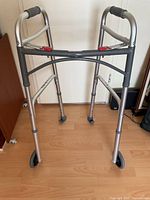 Full view of aluminum walker showing wheels, grips, and folding frame