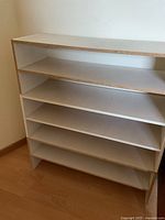 Three of the five stackable shoe racks shown, displaying two-shelf design and laminate finish