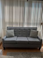 Front view of grey-blue three-seat sofa with pillows