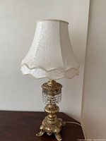 Full view of ornate brass table lamp with white shade
