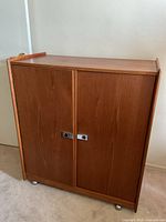 Front view of closed teak dresser showing two doors and recessed pulls
