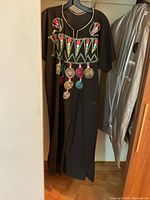 Front of black caftan dress showing colourful embroidery, V-neck, short sleeves, side slit hem
