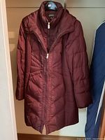 Front view of burgundy Jones New York quilted winter coat hanging in closet