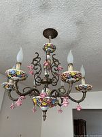 Full view of chandelier hanging from ceiling showing arms, floral details and scale