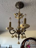 Full view of chandelier hanging from ceiling showing three arms, bobeches, porcelain roses, canopy