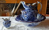 Large flow blue wash pitcher in basin with small vase, frontal view