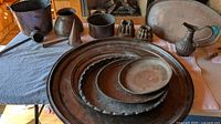 All copper items arranged; stack of chargers, bowl, moulds, bucket, ewer, ladles visible