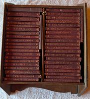 wood case with two columns of leatherbound volumes showing gilt titles