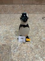 Front view of black and white glazed ceramic penguin figurine with label and price sticker visible.
