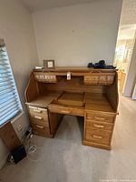 Front view of oak roll-top desk showing the roll-top closed and multiple drawers on left and right sides as well as smaller drawers inside the roll-top section.